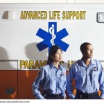 African male and Asian female paramedics next to ambulance